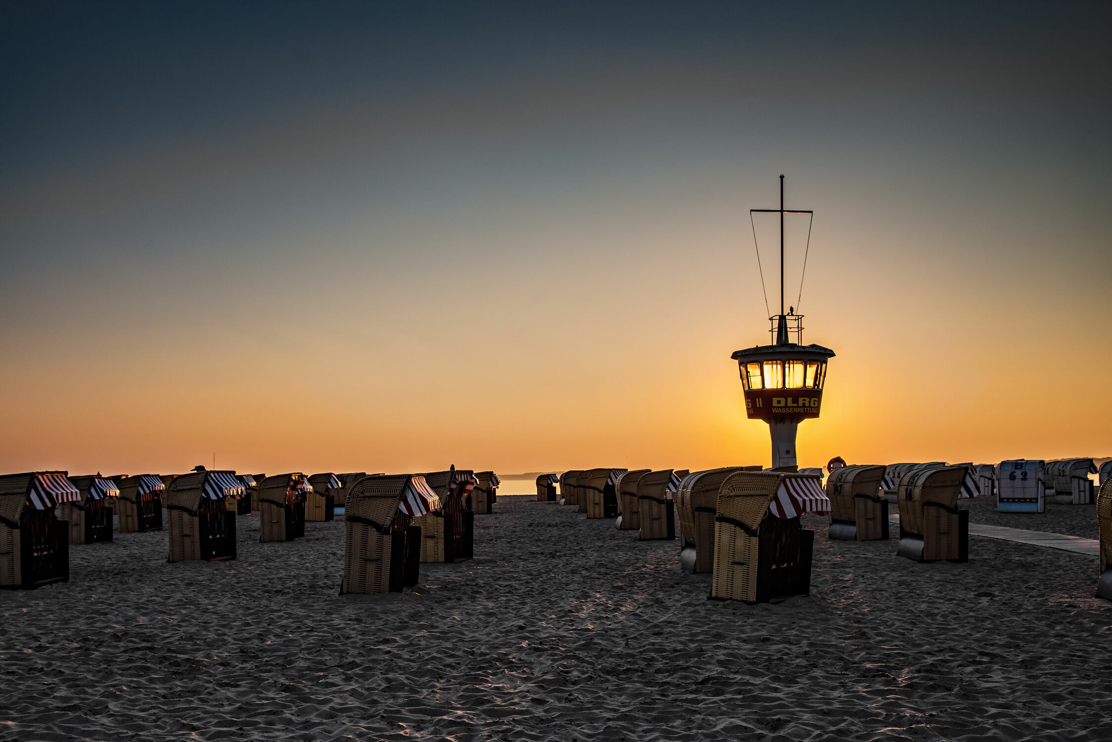 Bild mit Sonnenaufgang, Sonne, Strand, Strandkörbe, Ostsee, Gegenlicht, Licht, turm, Wasserwacht, Beobachtungsturm