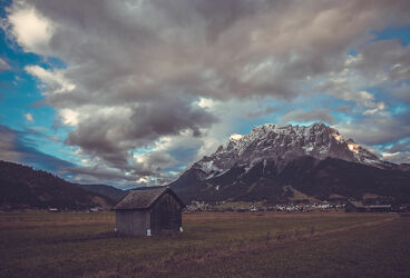 Bild mit Alpen, Wolken Himmel, Wolkenstruktur, Schnee in den Bergen, Holzhaus, Gewitterwolken, Wolkenfront, Zugspitze, Bergdorf
