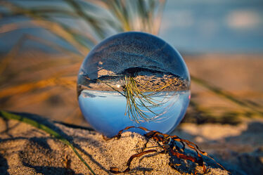 Glass ball on the beach of Baltic Sea. Reflection